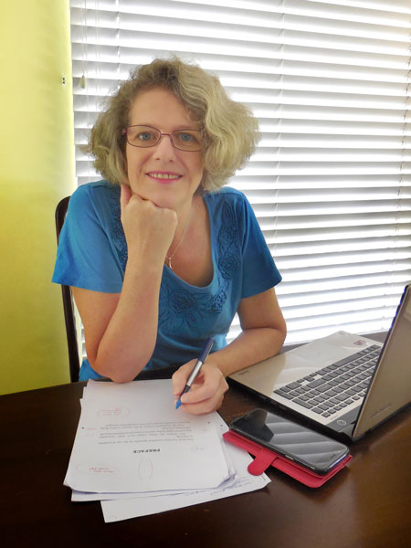 Emma Short virtual assistant working at a table with an open laptop close by